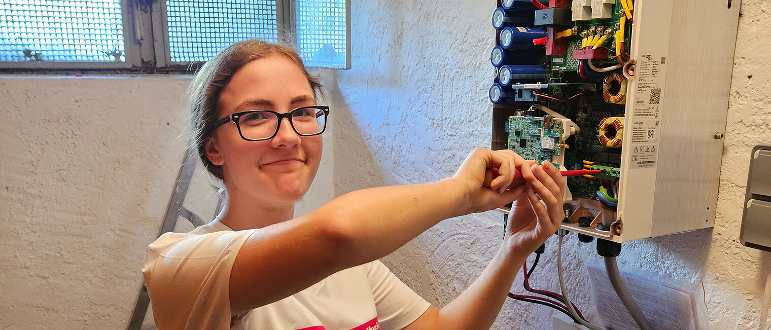 Energiewendehelferin Rosalie Rieger bei der Arbeit am Stromkasten in einem Keller.