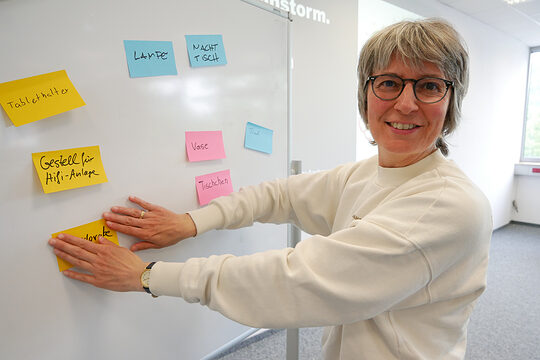 Dr. Maria klebt bunte Haftnotizen auf eine Tafel.